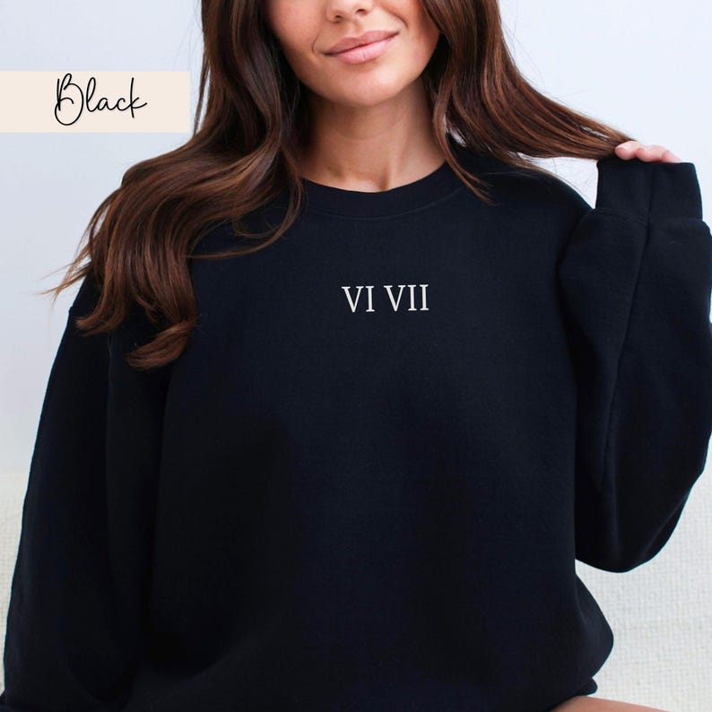 May include: Black crewneck sweatshirt with the text "VI VII" in white. The word "Black" is written in cursive in the upper left corner. The sweatshirt is a solid black color.