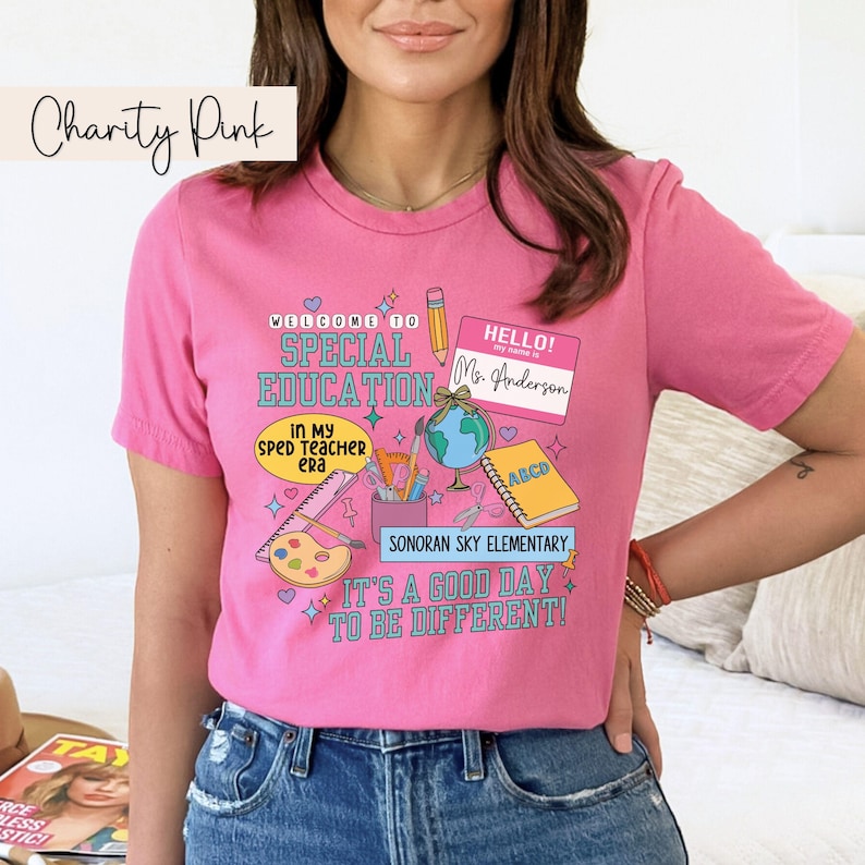 K&ouml;nnte beinhalten: Pinkes T-Shirt mit einem grafischen Design, das eine Willkommensnachricht zur sonderp&auml;dagogischen F&ouml;rderung, ein Namensschild mit der Aufschrift "Hallo! Mein Name ist Frau Anderson" und verschiedene Schulmaterialien zeigt. Der Text am unteren Rand des Designs lautet "Sonoran Sky Elementary. Es ist ein guter Tag, um anders zu sein!"