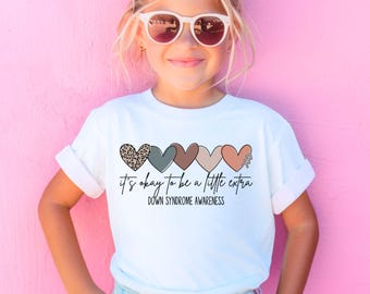 May include: White t-shirt with a line of five colorful hearts and the text "it's okay to be a little extra" and "Down Syndrome Awareness".