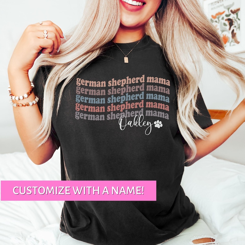 May include: Black t-shirt with the text "german shepherd mama" repeated five times in different colors. The text "Oakley" is written below the repeated text with a paw print.