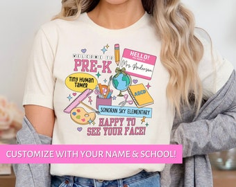 Peut inclure: T-shirt crème avec un motif graphique coloré pour les enseignants de pré-maternelle. Le motif comprend des fournitures scolaires, le texte "Welcome to Pre-K" et la phrase "Happy to see your face !" Le t-shirt est personnalisable.