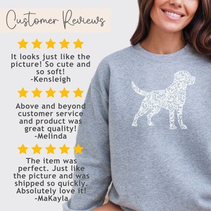 May include: A gray sweatshirt featuring a white floral dog design. The sweatshirt has the text "Customer Reviews" and customer testimonials with star ratings. The testimonials mention the product's quality and appearance.