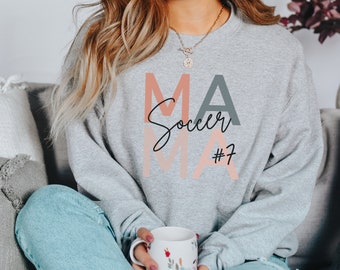 May include: Gray sweatshirt with the text "Soccer Mama #7" in pink, orange, and gray lettering.