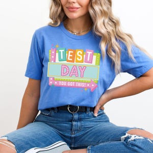 May include: A blue t-shirt with a colorful graphic that says "Test Day You Got This!"