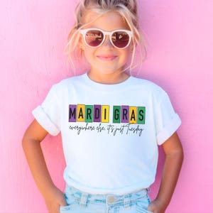 May include: White t-shirt with a colorful "Mardi Gras" graphic and the text "everywhere else. it's just Tuesday".