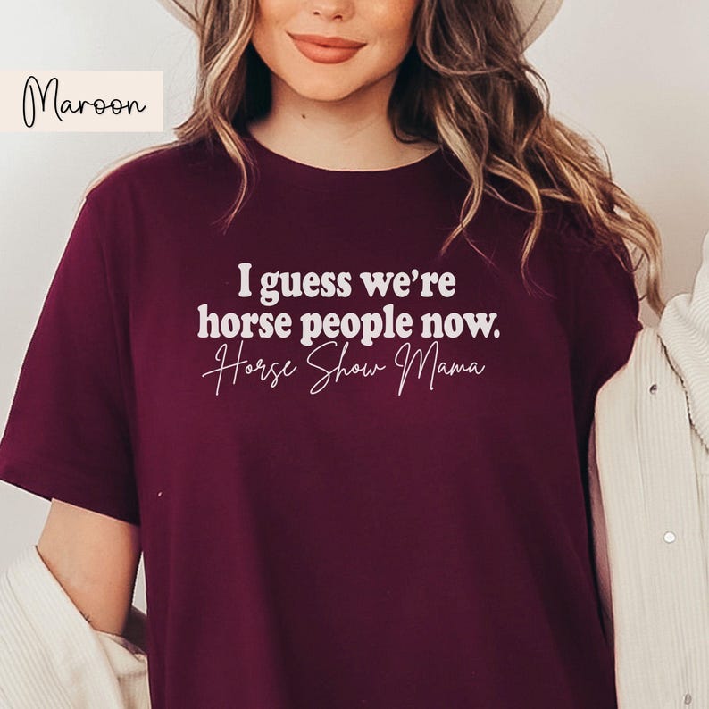 Peut inclure: Un t-shirt bordeaux avec le texte "I guess we're horse people now. Horse Show Mama" en blanc.