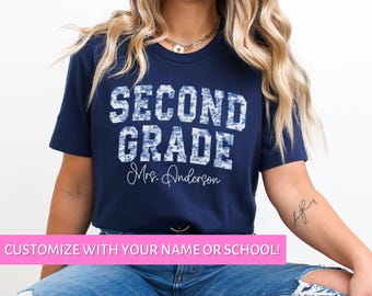 Könnte beinhalten: Ein marineblaues T-Shirt mit dem Text "SECOND GRADE" in Weiß mit einem blau-weißen Muster. Der Text "Mrs. Anderson" ist darunter in Weiß geschrieben.