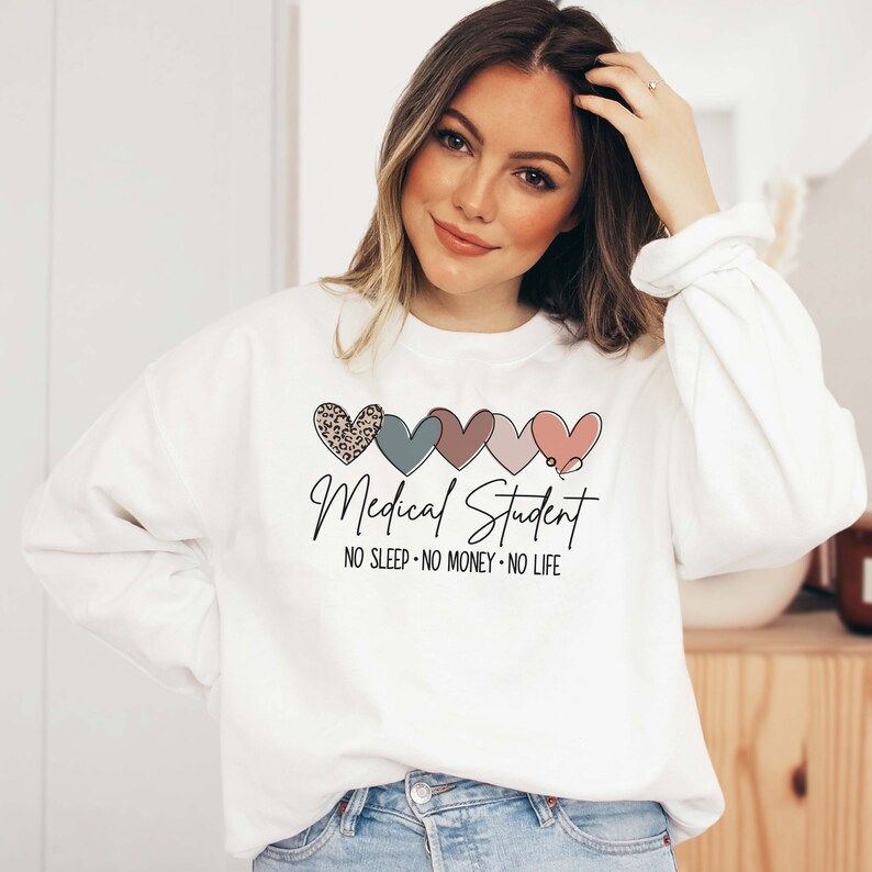 May include: White sweatshirt with a heart design. The design includes five hearts in various colors and patterns, with the text "Medical Student" and the phrase "NO SLEEP &bull; NO MONEY &bull; NO LIFE".