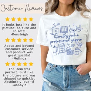 以下が含まれることがあります： 「literally just a professional yapper」と書いてある青いグラフィックデザインの白いTシャツ。グラフィックには、マイク、ラップトップ、メイクパレット、コーヒーカップ、その他のアイコンが含まれています。