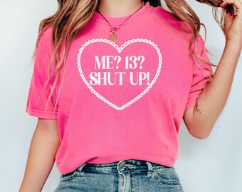 May include: Pink t-shirt with a white heart graphic that says "ME? 13? SHUT UP!"