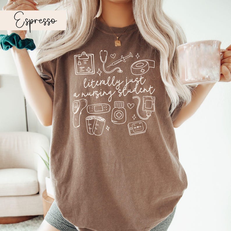 K&ouml;nnte beinhalten: Braunes T-Shirt mit einer wei&szlig;en Grafik von medizinischen Utensilien und dem Text "literally just a nursing student".