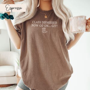 May include: A brown t-shirt with the text "Class Dismissed Now Go On... Git!" and a pair of cowboy boots printed on the front.
