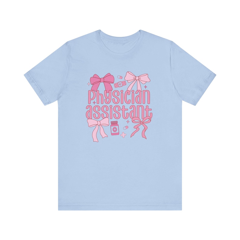 May include: Light blue t-shirt with a pink graphic design featuring the text "Physician assistant" with bows, pills, and bandages.