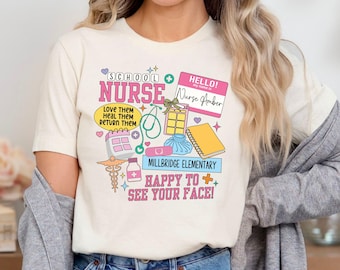 May include: A white t-shirt with a pink and blue graphic design that says "School Nurse". The graphic includes a stethoscope, a calendar, a bandage, a thermometer, a bottle of pills, and a notebook. The text also says "Love them, Heal them, Return them" and "Happy to see your face!"