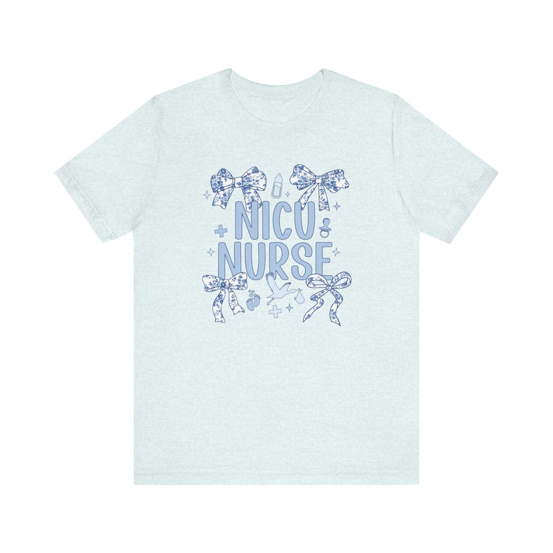 May include: Light blue t-shirt with a blue and white floral design. The shirt has the text "NICU NURSE" with a variety of small blue and white icons.