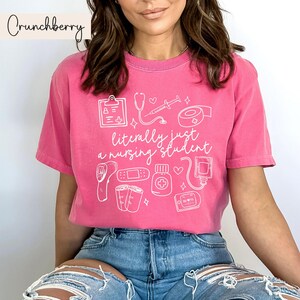 K&ouml;nnte beinhalten: Pinkes T-Shirt mit einem wei&szlig;en Grafikdesign von medizinischen Instrumenten und dem Text "im Grunde nur ein Krankenpflegesch&uuml;ler".