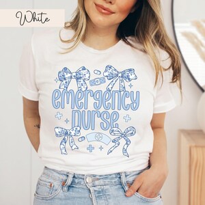 May include: White t-shirt with a blue and white floral design and the text "emergency nurse".