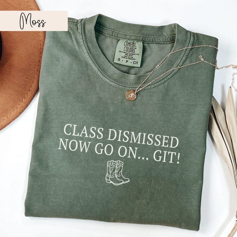 May include: A green t-shirt with the text "CLASS DISMISSED NOW GO ON... GIT!" in white. The shirt features a small outline of two cowboy boots.