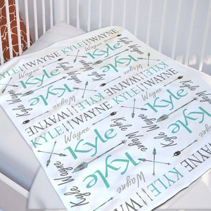 May include: White baby blanket with a repeating pattern of the names "Kyle" and "Wayne" in teal and gray text with arrows.