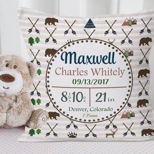 May include: A white and brown baby pillow with a woodland theme. The pillow features a circular design with the name Maxwell Charles Whitely, the date 09/13/2017, and the baby's birth stats: 8 lbs 10 oz and 21 inches. The pillow also features a brown bear, a deer, and a mountain design.
