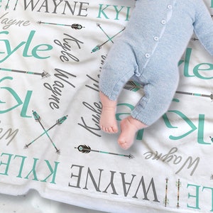 May include: A white baby blanket with the names "Kyle" and "Wayne" repeated in a turquoise and gray font. The blanket is decorated with turquoise and gray arrows. A baby is lying on the blanket.