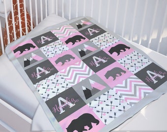 Könnte beinhalten: Eine rosa und graue Babydecke mit Patchwork-Muster, das Bären, Berge, Pfeile und den Namen "Amelia" zeigt.