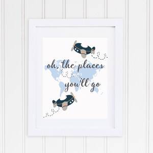 May include: A white framed print with a blue world map and two blue airplanes. The text "oh, the places you'll go" is written in black cursive.