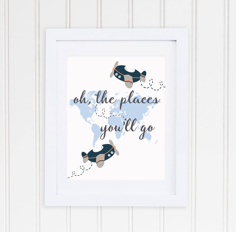 May include: A white framed print with a blue world map and two blue airplanes. The text "oh, the places you'll go" is written in black cursive.