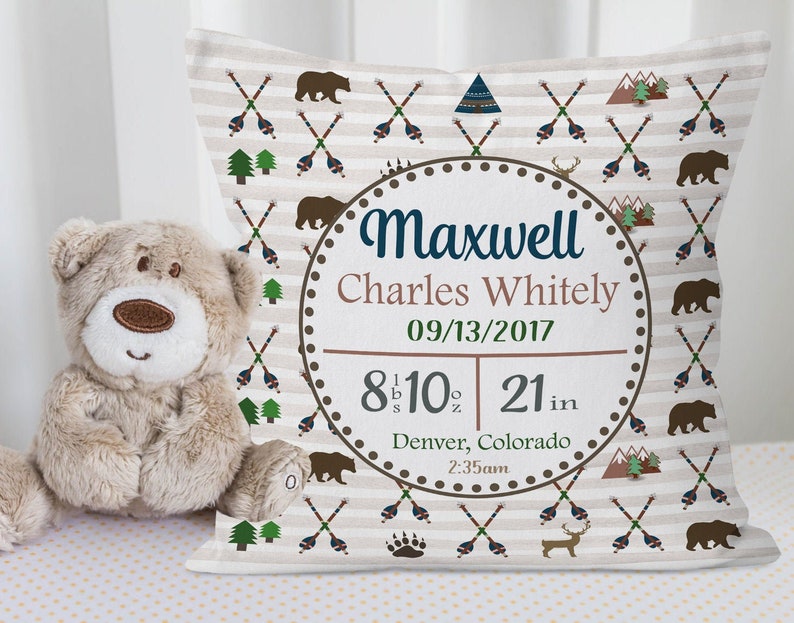 May include: A white and brown baby pillow with a woodland theme. The pillow features a circular design with the name Maxwell Charles Whitely, the date 09/13/2017, and the baby's birth stats: 8 lbs 10 oz and 21 inches. The pillow also features a brown bear, a deer, and a mountain design.