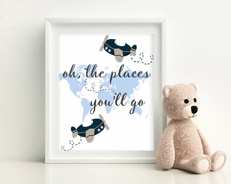 May include: A white framed print with a blue world map and two blue airplanes. The text "oh, the places you'll go" is written in black cursive font.