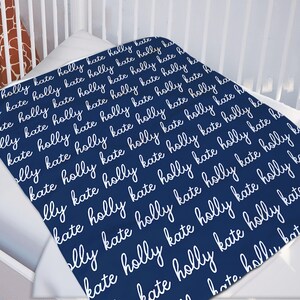May include: A navy blue baby blanket with the names "Holly" and "Kate" repeated in white cursive writing.