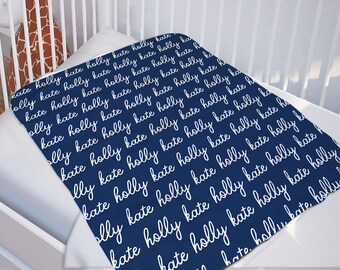 May include: A navy blue baby blanket with the names "Holly" and "Kate" repeated in white cursive writing.