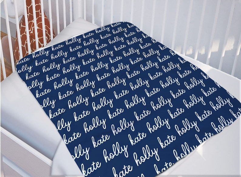 May include: A navy blue baby blanket with the names "Holly" and "Kate" repeated in white cursive writing.