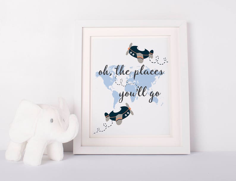 May include: A white framed print with a blue world map and two blue airplanes. The text "oh, the places you'll go" is written in black.
