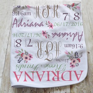 May include: A white baby blanket featuring floral illustrations in pink and green, with the name Adriana, the date 06/17/2016, the time 9:16am, the weight 7 pounds 8 ounces, the length 21 inches, and the monogram initials A R F printed in various fonts.