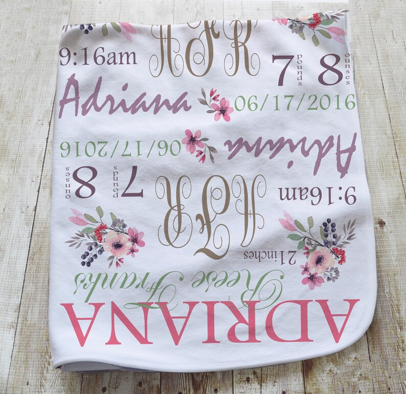 May include: A white baby blanket featuring floral illustrations in pink and green, with the name Adriana, the date 06/17/2016, the time 9:16am, the weight 7 pounds 8 ounces, the length 21 inches, and the monogram initials A R F printed in various fonts.