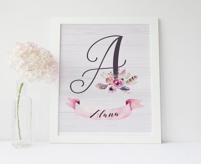 May include: A white framed print with a floral design and the letter "A" in black. The name "Alana" is written in a pink banner below the letter.