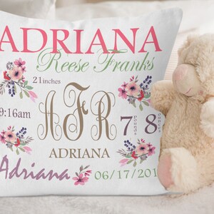 Puede incluir: Una almohada blanca con un dise&ntilde;o floral y el nombre "Adriana" en letras rosas. La almohada tambi&eacute;n incluye la informaci&oacute;n de nacimiento del beb&eacute;: 9:16 am, 7 libras 8 onzas y 21 pulgadas. El texto "Reese Franks" tambi&eacute;n est&aacute; incluido en letras verdes.