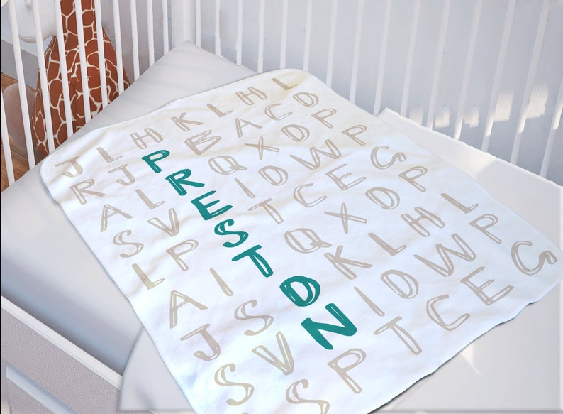 May include: White baby blanket with a light brown alphabet pattern. The name "Preston" is spelled out vertically in teal.