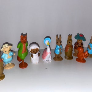May include: A set of ten Beatrix Potter figurines, including Peter Rabbit, Mrs. Tiggy-Winkle, Jemima Puddle-Duck, and Mr. McGregor. The figurines are made of plastic and are painted in bright colors.