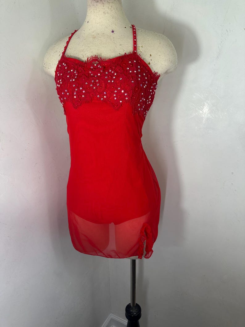 May include: A red dance costume with a sheer overlay and a lace bodice embellished with rhinestones.