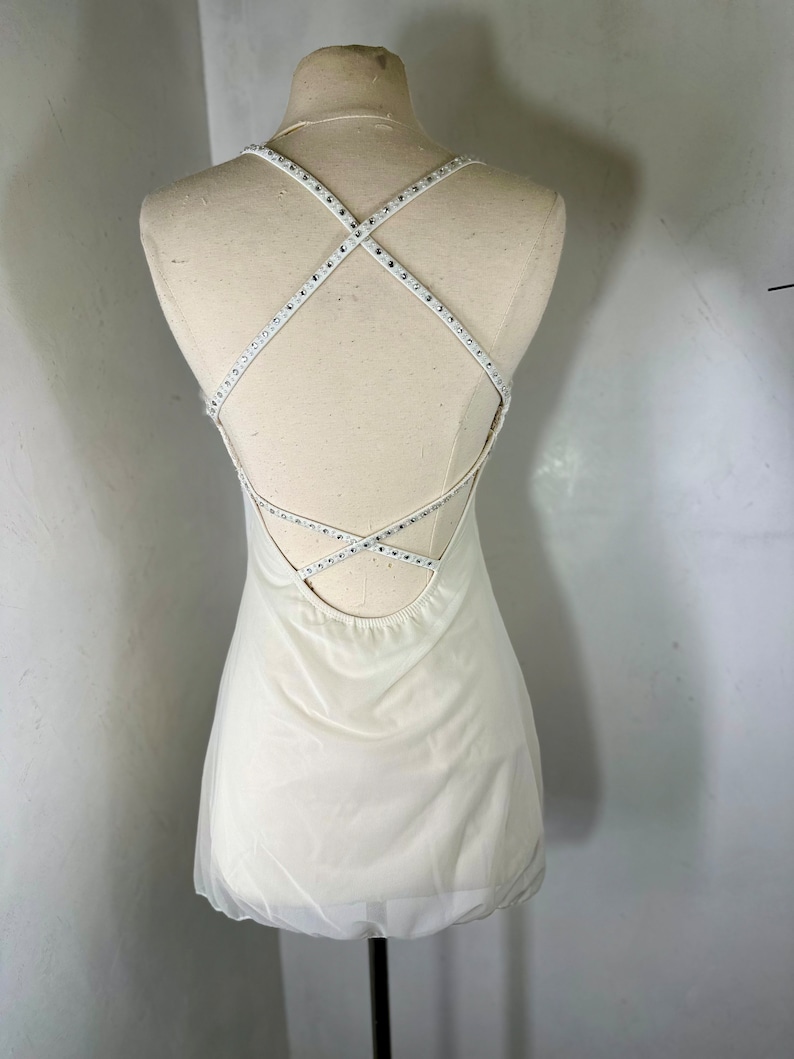 May include: A white sleeveless dress with a criss-cross back detail featuring rhinestones.