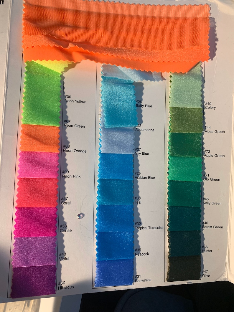 May include: A fabric colour swatch card displaying a range of vibrant colours. The card shows swatches of neon yellow, green, pink, orange, coral, cerise, violet, and hibiscus. Additional colours include baby blue, aquamarine, sky blue, teal, and tropical turquoise.