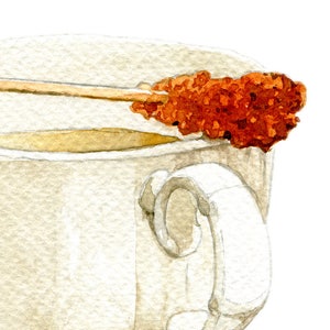 May include: A white ceramic teacup with a brown handle, filled with light brown tea. A brown sugar stick is resting on the rim of the cup.