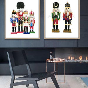May include: Two framed watercolor paintings of nutcracker figurines. The first painting shows five nutcrackers in a row, with the tallest in the center. The second painting shows two nutcrackers standing side-by-side.