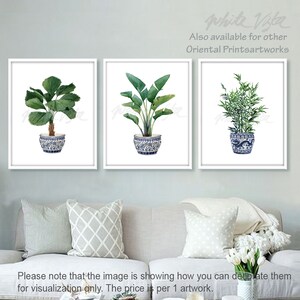 May include: Three watercolor paintings of plants in blue and white ceramic pots. The plants are a palm tree, a banana leaf plant, and bamboo. The paintings are framed in white.