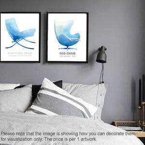 May include: Two framed prints of watercolor illustrations of iconic chairs. The left print features a blue Barcelona chair with the text "Barcelona Chair" and "Ludwig Mies van der Rohe 1929". The right print features a blue Egg chair with the text "Egg Chair" and "Arne Jacobsen: 1958".