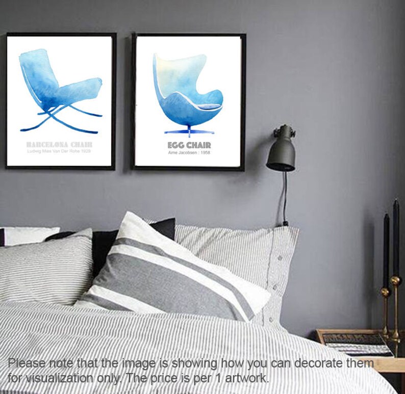 May include: Two framed prints of watercolor illustrations of iconic chairs. The left print features a blue Barcelona chair with the text "Barcelona Chair" and "Ludwig Mies van der Rohe 1929". The right print features a blue Egg chair with the text "Egg Chair" and "Arne Jacobsen: 1958".