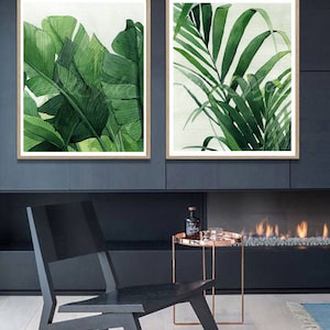 K&ouml;nnte beinhalten: Zwei gerahmte Aquarellbilder von tropischen Bl&auml;ttern. Das Bild links zeigt gro&szlig;e gr&uuml;ne Bananenbl&auml;tter. Das Bild rechts zeigt kleinere gr&uuml;ne Palmbl&auml;tter.