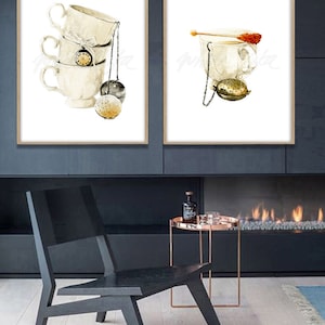 May include: Two watercolour paintings of teacups with tea infusers. The first painting shows a stack of three teacups with a tea infuser hanging from the top cup. The second painting shows a single teacup with a tea infuser and a sugar stick.
